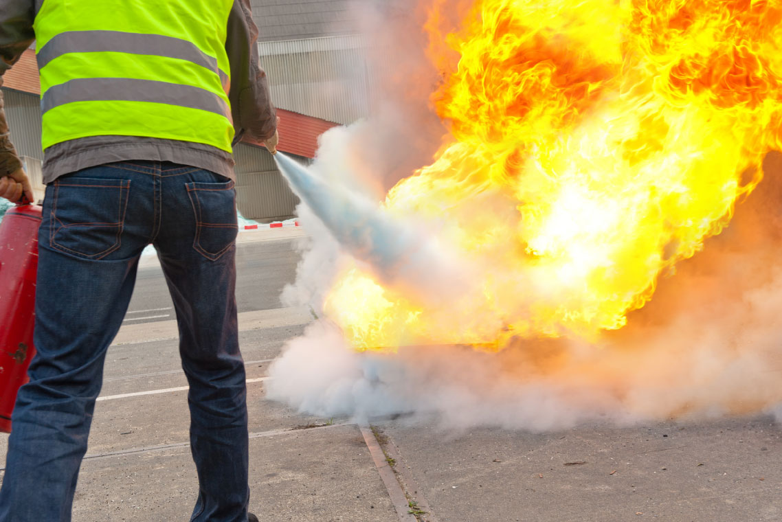 Dorset Fire Protection providing fire safety training, one man putting out a fire with an extinguisher