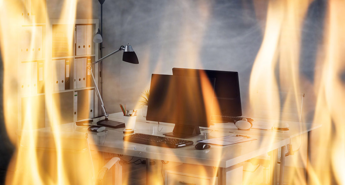 A computer desk with desktop and lamp on on fire