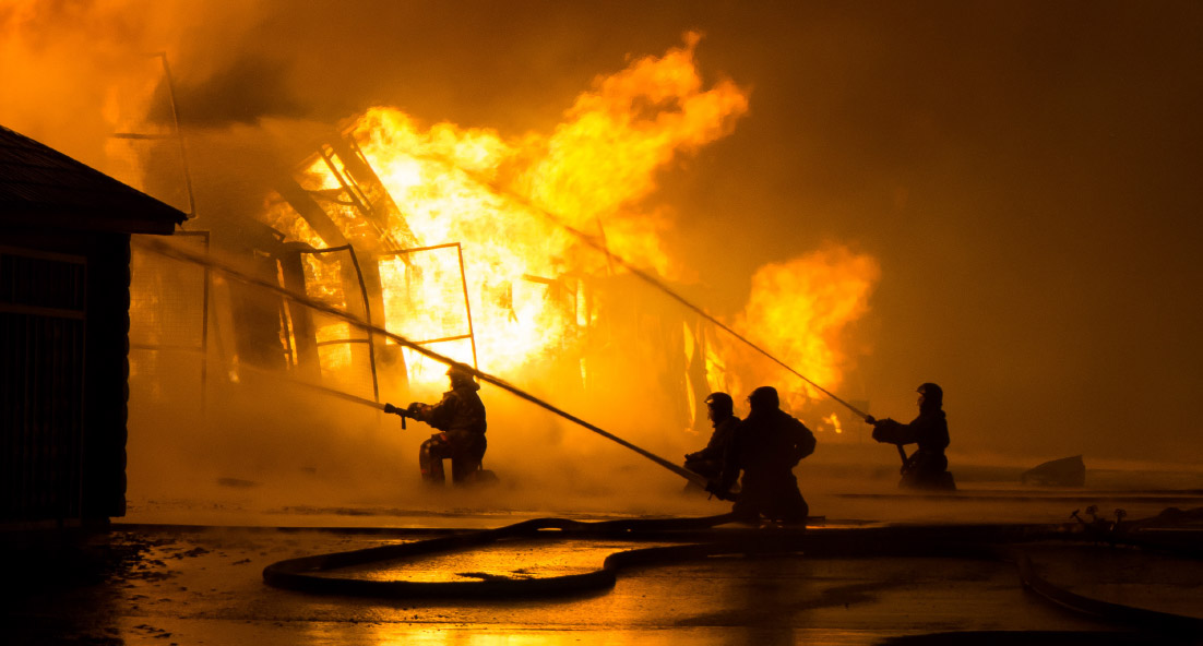 A group of firemen putting out a building fire with fire extinguishers and water hoses