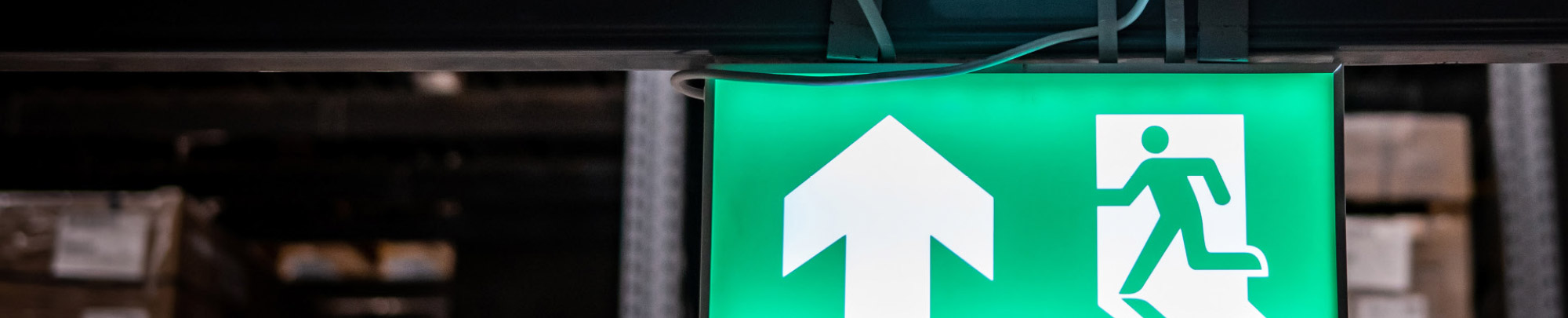 A green 'emergency exit' sign on top of a doorway